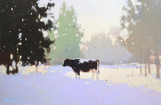 Cow standing in a snowy landscape with trees in the background