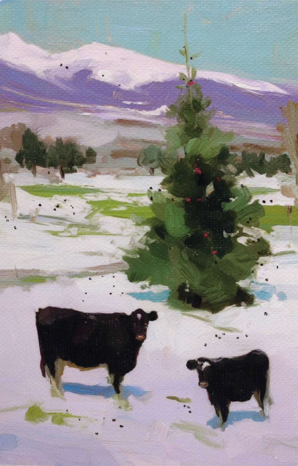 Two cows standing in a snowy landscape with a Christmas tree and mountains in the background.