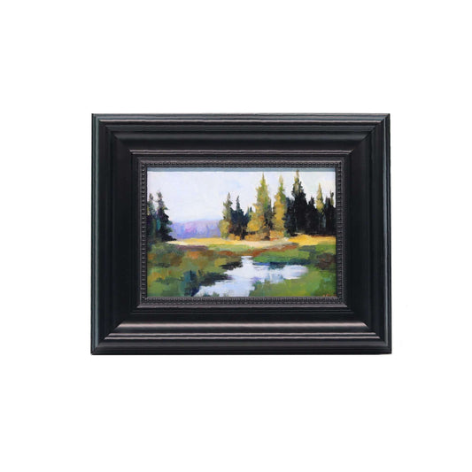 Framed painting of a landscape with trees and a pond on a white background